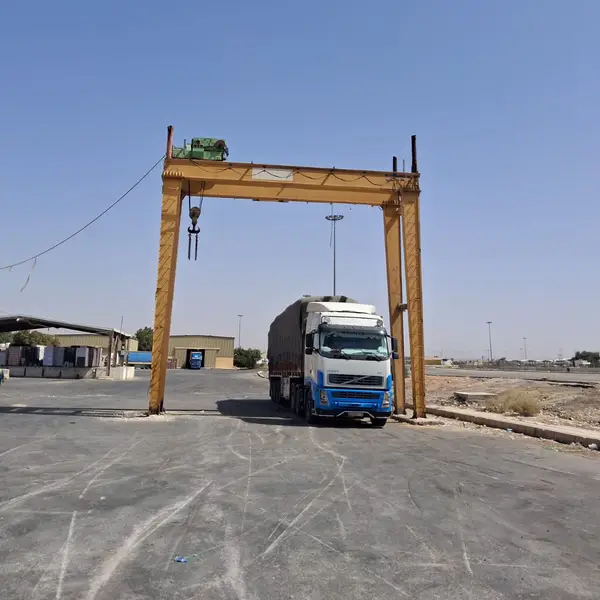 Gantry crane lifting over a loaded trailer at a border yard